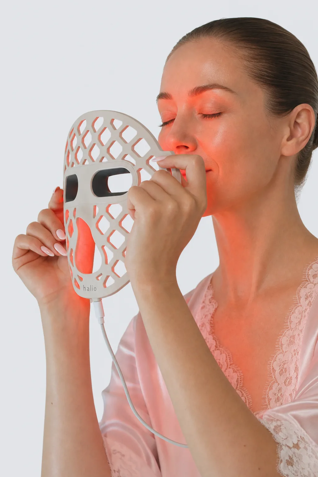 A woman in her late thirties holding the lit PureGlow mask beside her cheek